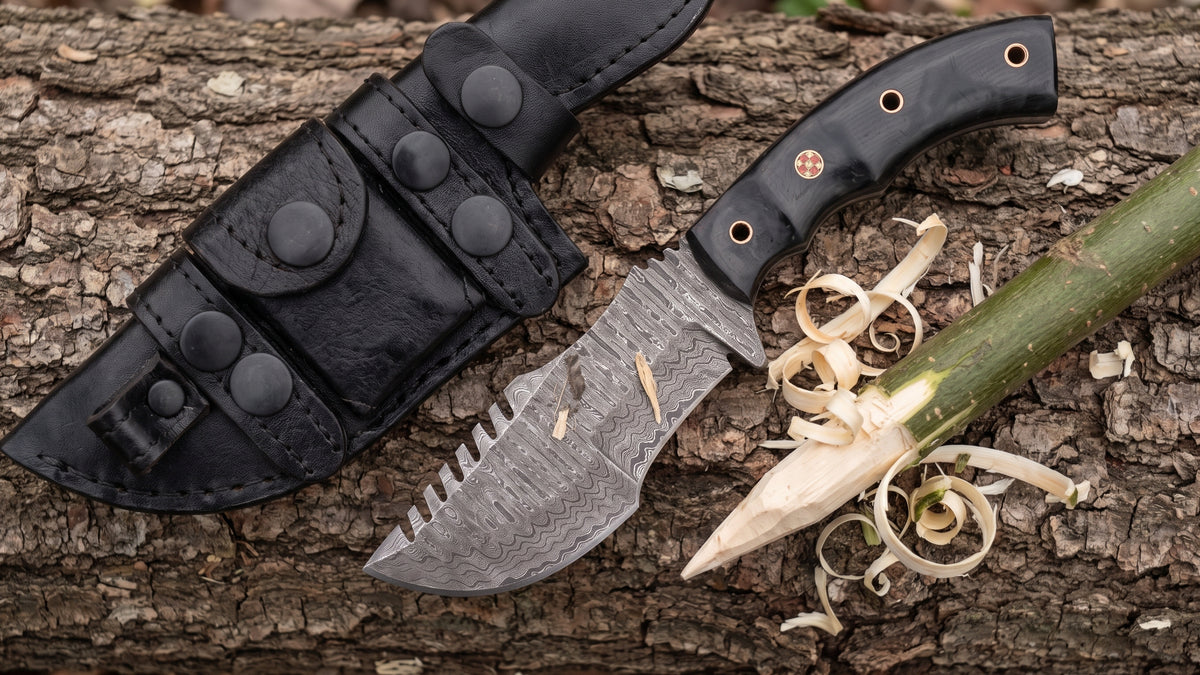 Tracker Damascus knife beside a half carved green stick and fresh wood shavings on a log at camp