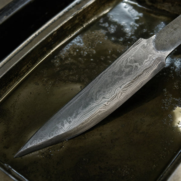 A Damascus blade in the acid bath, the pattern coming up