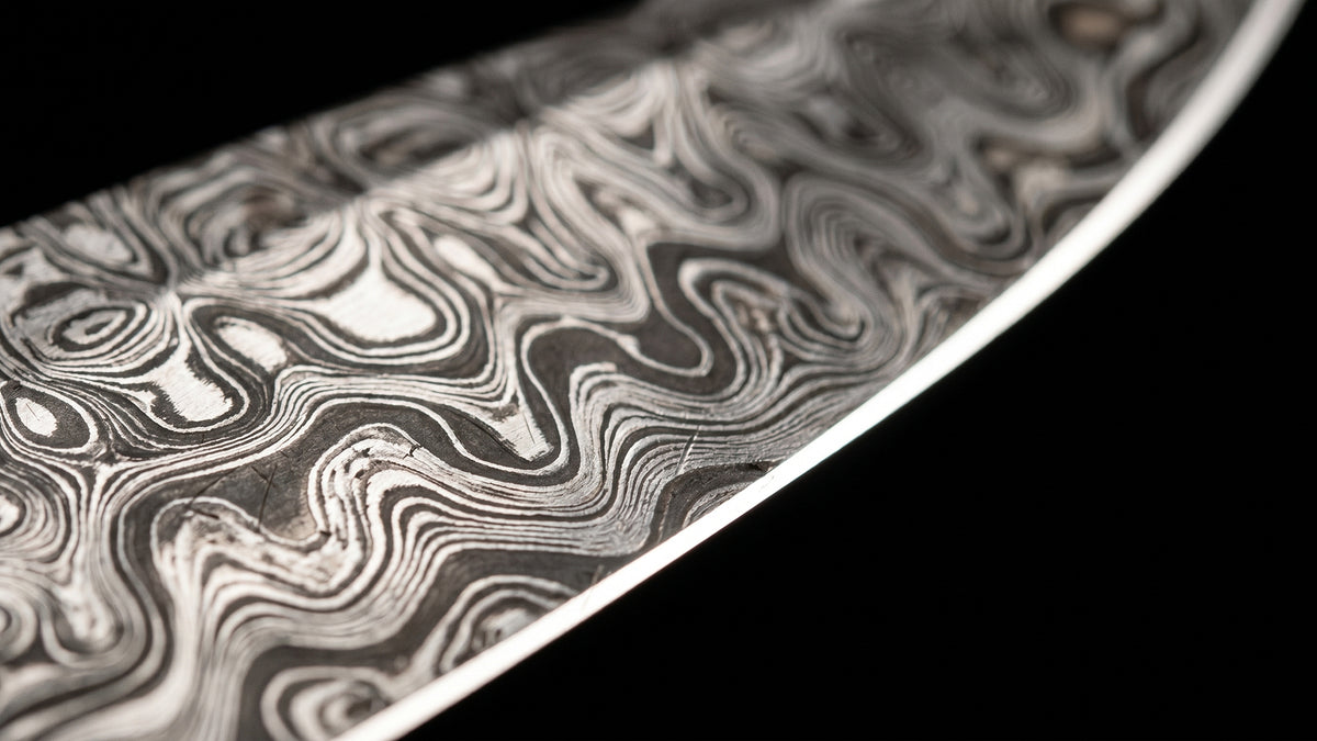 Macro of the Damascus pattern running along a polished blade to the edge